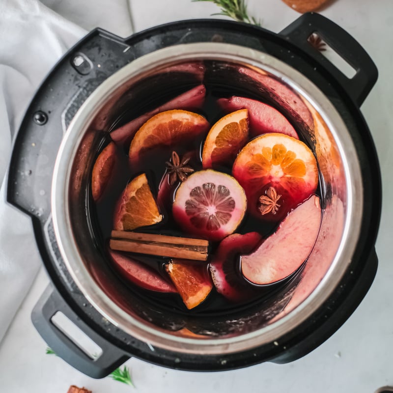 Apple slices, oranges, lemons and spices in red wine | Irish American Mom Sliced fruit, cinnamon stick and star anise in red wine in a pot