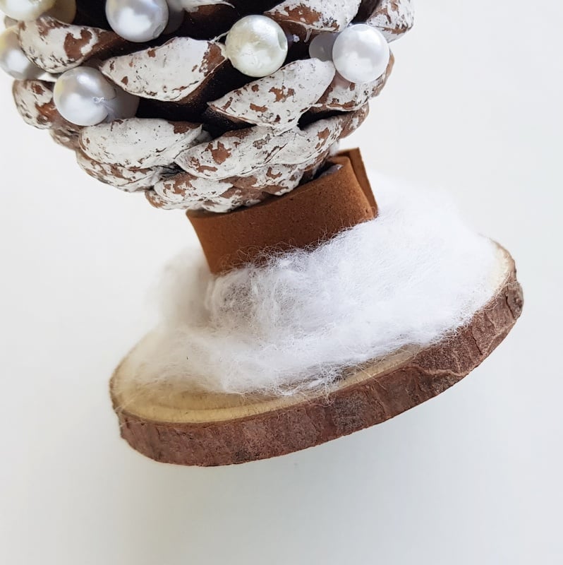 Cotton wool used to create snow at the base of a homemade pine cone Christmas tree decoration or ornament | Irish American Mom A cotton ball stretched out over a wooden disc to look like snow on a pine cone Christmas tree craft