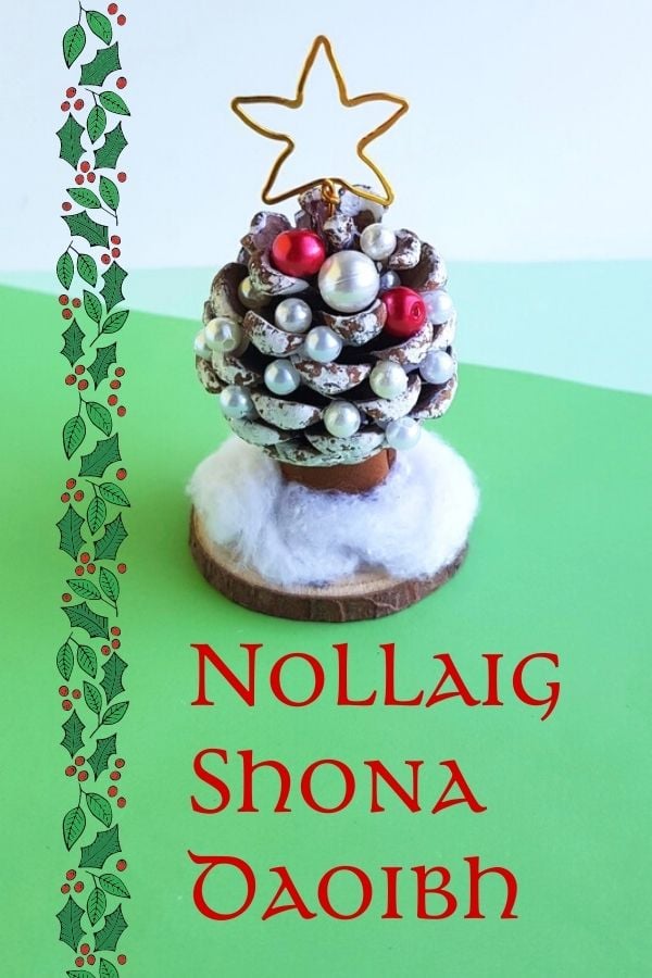 Nollaig Shona Daoibh | Irish American Mom A pine cone Christmas tree on a wooden circle with a holly border and text on a graphic