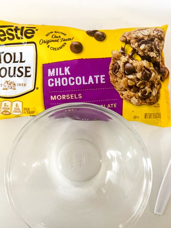 Packet of chocolate chips beside a bowl | Irish American Mom A yellow packet of chocolate chips with a picture of a chocolate chip cookie and text beside a glass bowl