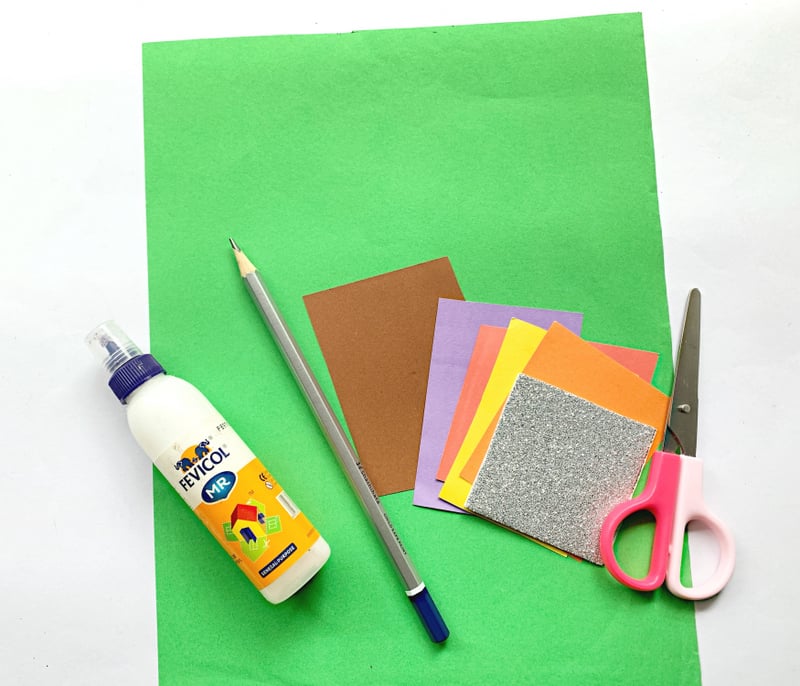 Natural | Irish American Mom Green sheet of paper with small square cuttings of brown, purple, yellow, orange and glitter paper bside a scissors, a pencil and glue