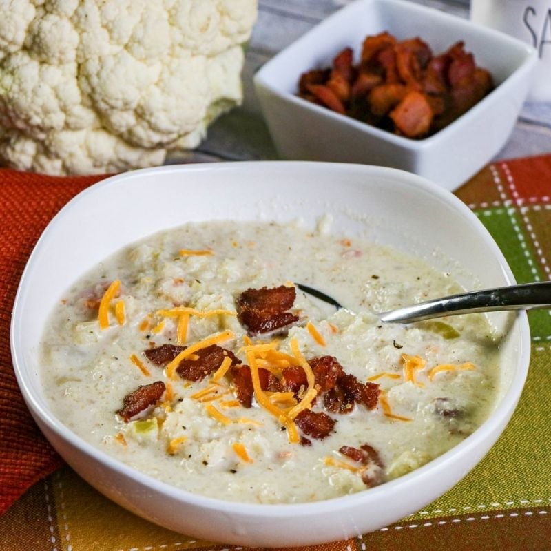 A bowl full of cauliflower chowder with bacon bits and a spoon | Irish American Mom A white bowl of cauliflower soup with bacon bits
