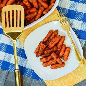 Baby carrots on a white plate displayed beside a casserole of baked carrots