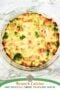 Whole baked crustless quiche in a glass dish with ham, broccoli, and melted cheese, golden brown on top.