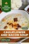 A bowl of creamy cauliflower soup topped with crispy bacon bits and shredded cheese, with a head of cauliflower in the background with amber background text banner with white text.