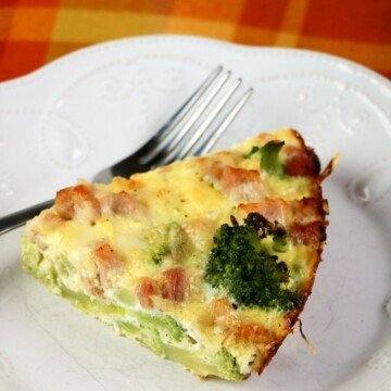 Slice of crustless quiche on a white plate with a fork