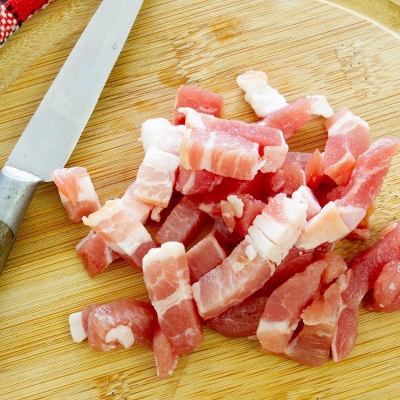 Chopped bacon on a wooden chopping board with a knife