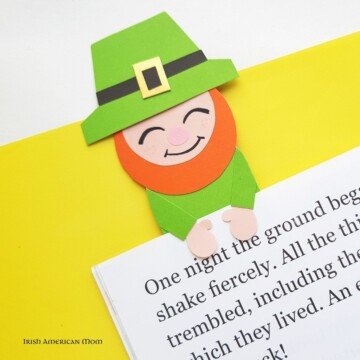 Paper leprechaun with green hat holding a book page by his hands