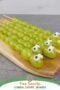 Green grapes threaded onto skewers and arranged to look like playful snakes with candy eyes, displayed on a wooden board for a fun St. Patrickโs Day snack for kids