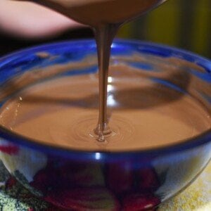 Melted chocolate dripping from a spoon into a bowl