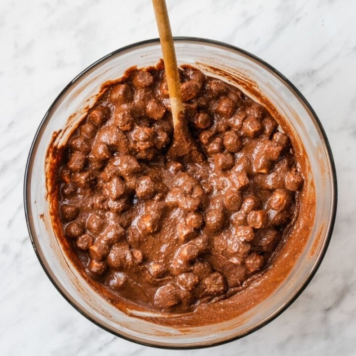 No bake mixture for Rolo Rocky Roads | Irish American Mom Melted chocolate, cookies, and marshmallows in a bowl with a wooden spoon