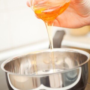 Golden syrup being poured from a glass bowl into a saucepan
