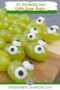Overhead view of grape skewers arranged in straight lines, each decorated with candy eyes to create green snake snacks.