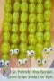 Close-up of green grape snakes with candy eyes attached to the front grape, arranged on a wooden cutting board for a festive holiday snack.