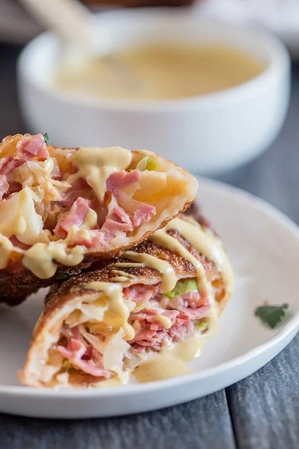 Egg roll with corned beef filling halved and open on a plate