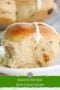 Close-up of a soft hot cross bun with white icing cross on top, showing fluffy interior with dried fruit pieces, labeled as an Easter recipe.