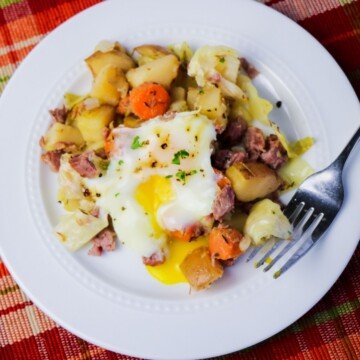 Corned beef hash with an egg on top on a white plate with a fork
