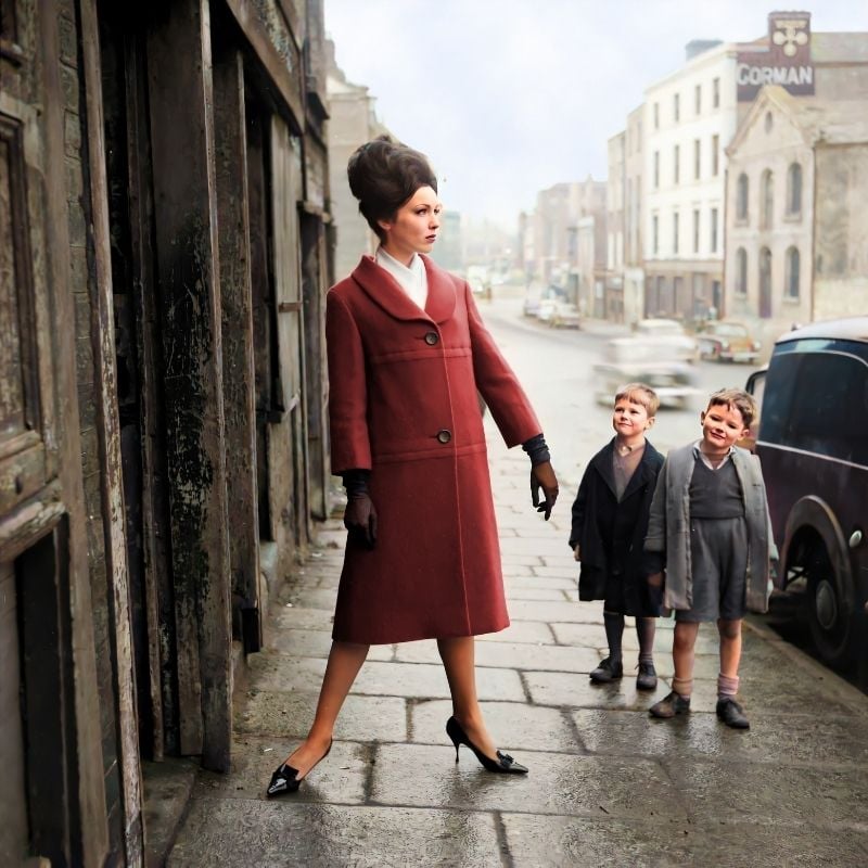 A woman in a red coat on a street beside two boys