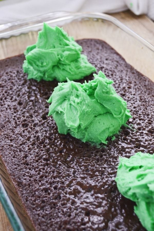 Topping brownies with green frosting | Irish American Mom Three dollops of green frosting on a pan of brownies