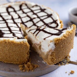 Lifting a slice of cake with cream and chocolate drizzle from a pie