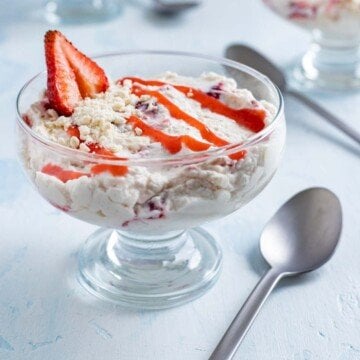 Strawberry sauce on a creamy dessert in a glass dish with a spoons