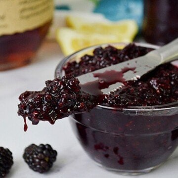 Blackberry jam on a knife on a bowl of jam