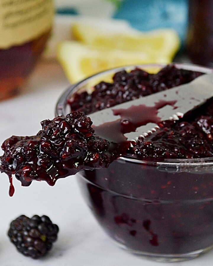 Blackberry jam on a knife on a bowl of jam