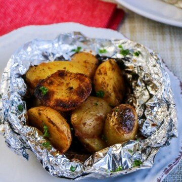 Potatoes in a foil packet on a white plate
