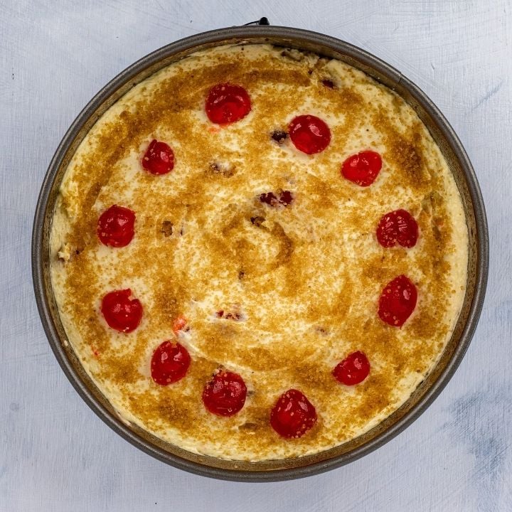 Cherries and sugar on top of the batter for an Irish Cherry tea cake | Irish American Mom Circle of cherries on top of cake batter in a baking pan