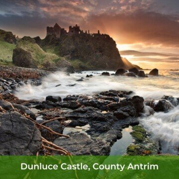 Ruined stone castle beside the shoreline with the sun setting and a text banner