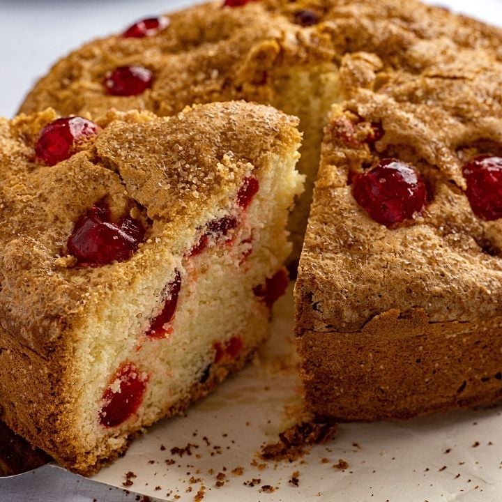 Irish Cherry tea cake slice being taken from a whole cake | Irish American Mom Slice of cherry cake being cut from a whole cake