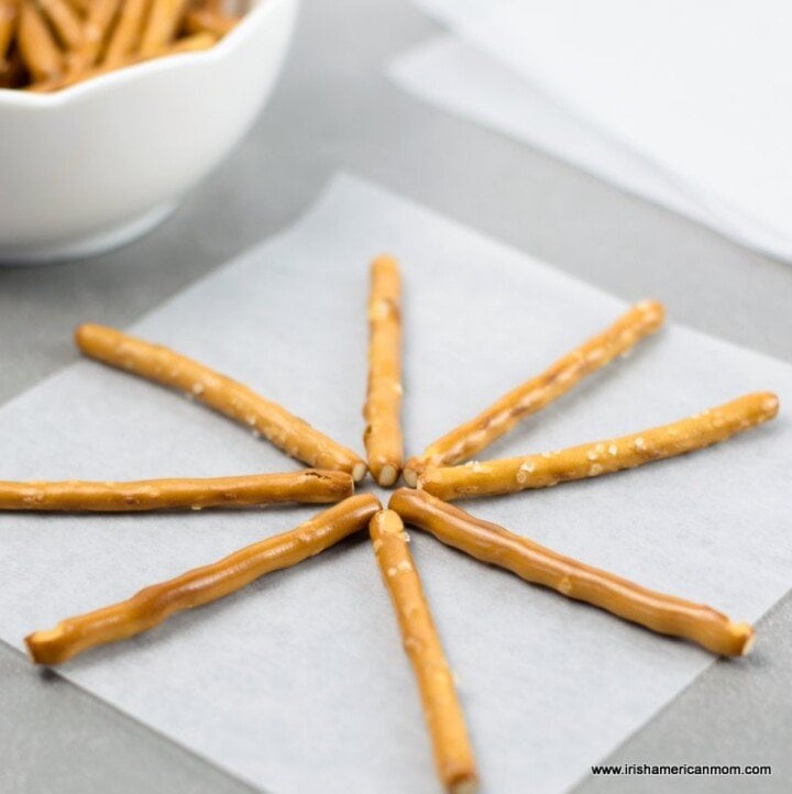 Pretzel sticks layed on parchment to form the spines of a spiders web | Irish American Mom Pretzel sticks laid out on parchment paper in spiral spoke pattern