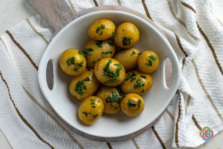 Bowl of buttered parsley potatoes | Irish American Mom Potates in their skins with parsley in a dish