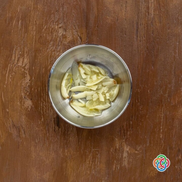 Mashing boiled garlic cloves for smashed potatoes | Irish American Mom Cooked garlic cloves in a dish