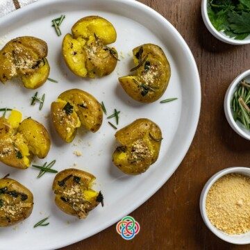 Smashed potatoes beside bowls of herbs and cheese