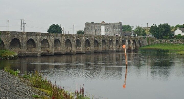 Building beside an arched stone bridge over a river