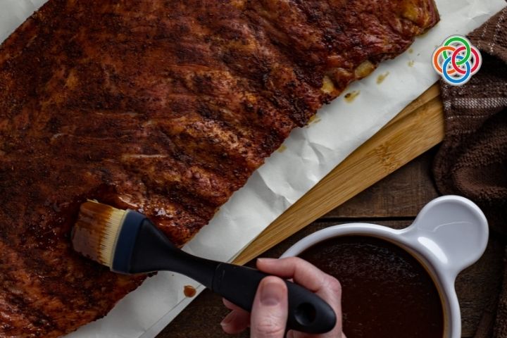 Brushing barbecue sauce on ribs
