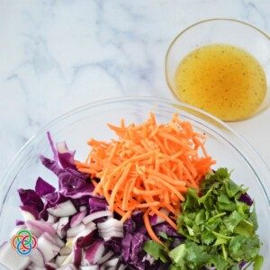 Bowl of dressing beside a bowl of vegetables