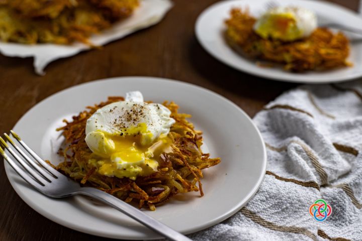 Broken poached egg with yolk running over a potato hash cake | Irish American Mom Broken poached egg with yolk on a potato cake