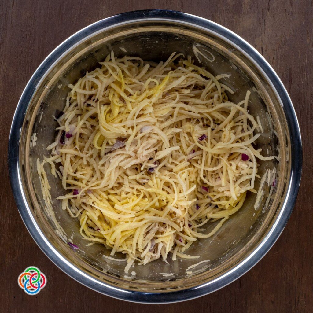 Grated potatoes with onion flour and beaten egg n a bowl | Irish American Mom Beaten egg over grated potatoes in a bowl