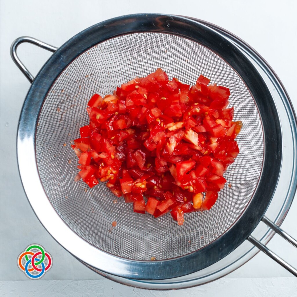 Straining diced tomatoes to remove excess juices | Irish American Mom Diced tomatoes in a strainer over a bowl