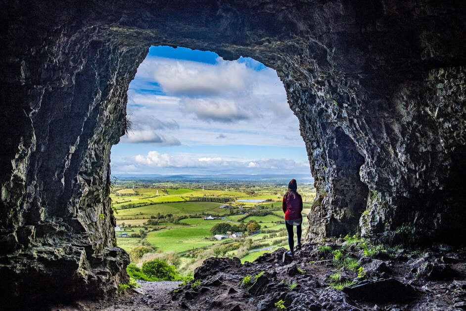Person in a cave looking out over a green landscape