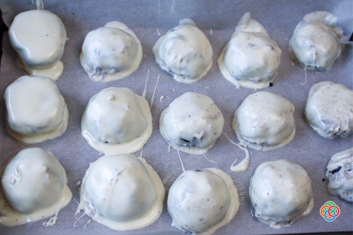 Coating patriotic oreo truffles in white chocolate | Irish American Mom White chocolate covered truffles on a baking tray