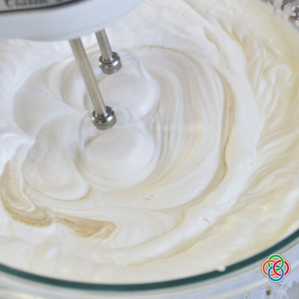 Whipping cream in a bowl for raspberry and vanilla wafer ice box cake | Irish American Mom Whipping cream with an electric mixer