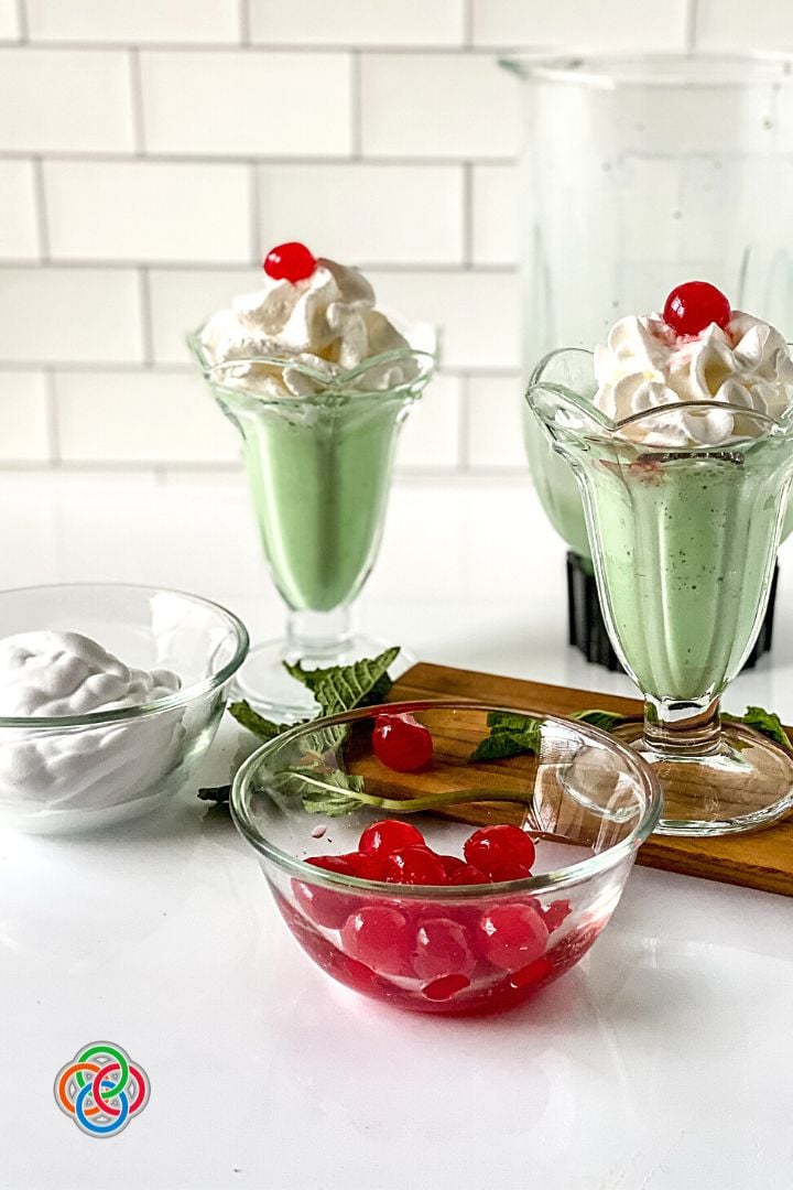 Making shamrock shakes at home | Irish American Mom Green milk shakes with a blender, and bowls of cream and cherries