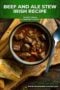 Bowl of hearty beef and ale stew with chunks of beef, carrots, and celery in a rich dark broth, served with crusty bread on a wooden board with Irish-themed text above.
