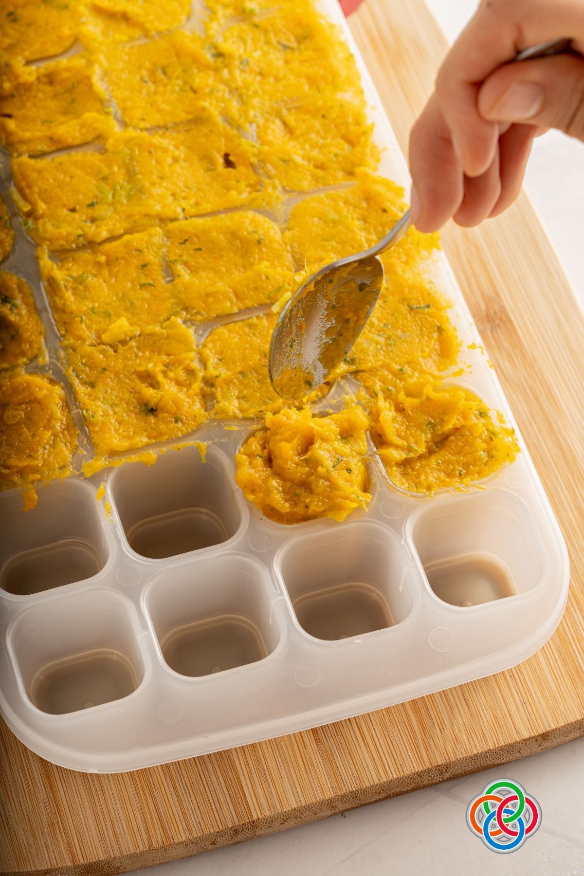 Filling an ice cube tray with mixture for vegan vegetable stock cubes | Irish American Mom Using a spoon to fill an ice cube tray with vegetable paste