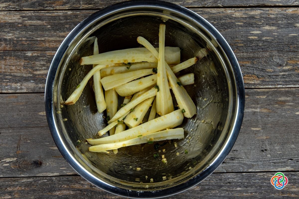 Peeled and sliced parsnips mixed with honey in a bowl | Irish American Mom Slices of parsnips with herbs in a bowl