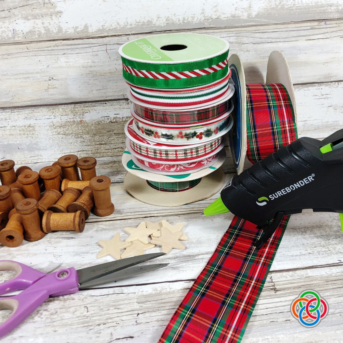 Materials for making sewing spool Christmas tree ornaments | Irish American Mom Rolls of ribbon, glue gun, scissors and empty wooden spools
