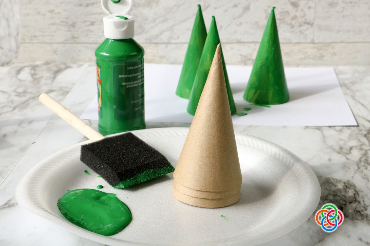 Paper mache cones for tree crafts painted green | Irish American Mom Cardboard craft cones with green paint and a foam brush